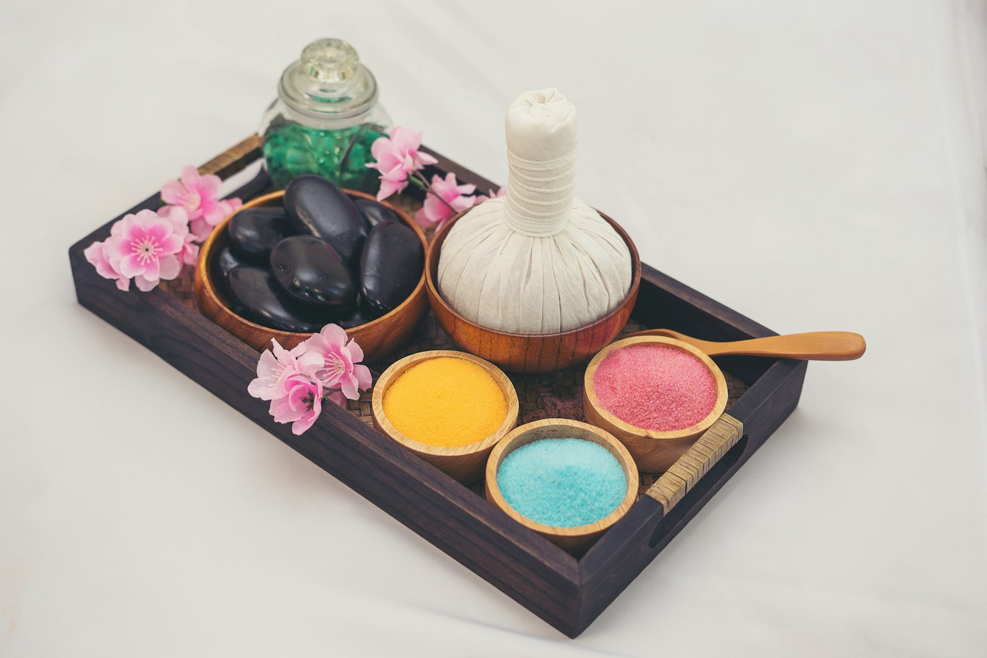 Massage-Steine und Badesalz auf einem Holztablett.