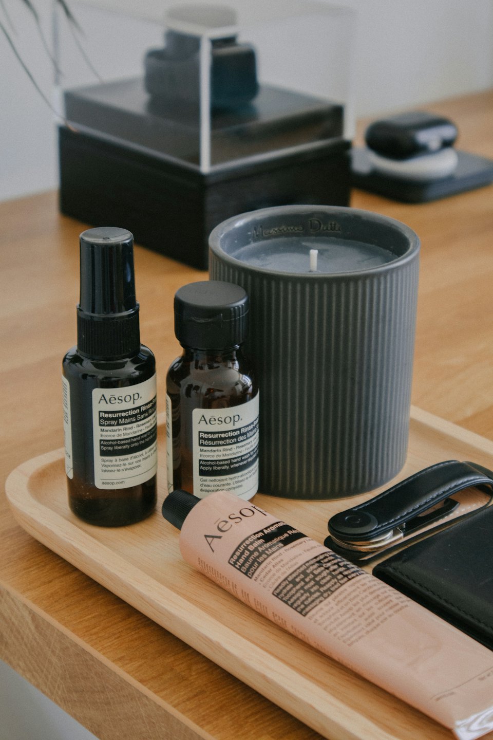 Holztablett mit Aesop-Flaschen, Kerze und Brieftaschenartikeln.